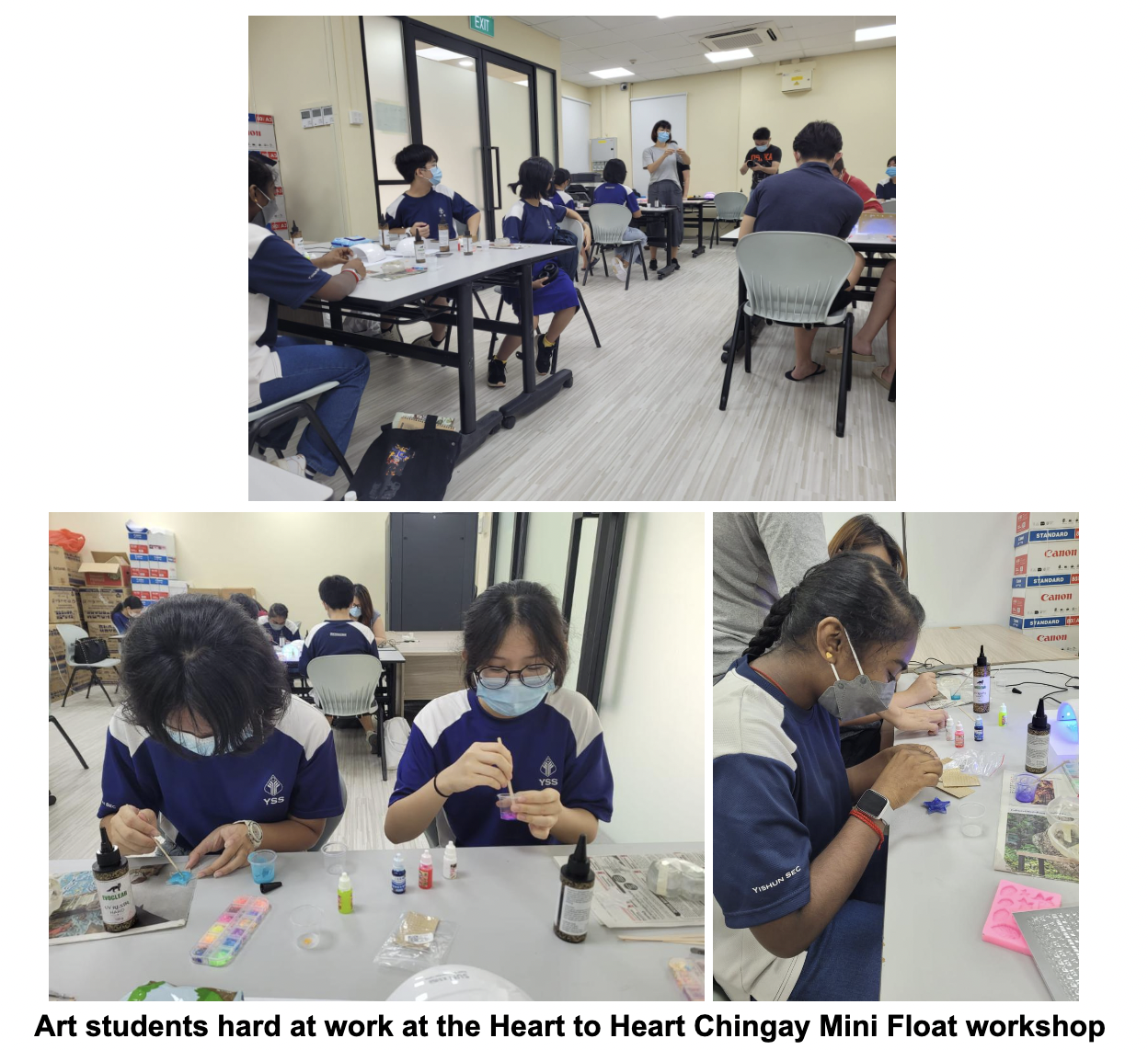 Students in blue uniforms and masks work on craft projects with paints and tools at tables in a classroom.